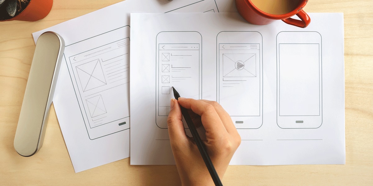 A UX designer's hands doing wireframing on paper